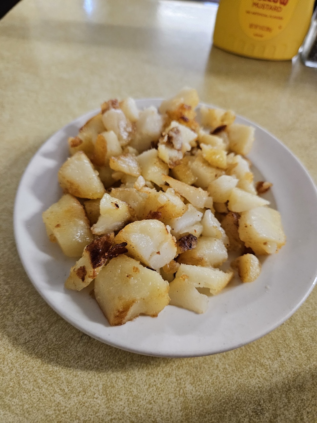 A small plate of golden, griddled home fries.