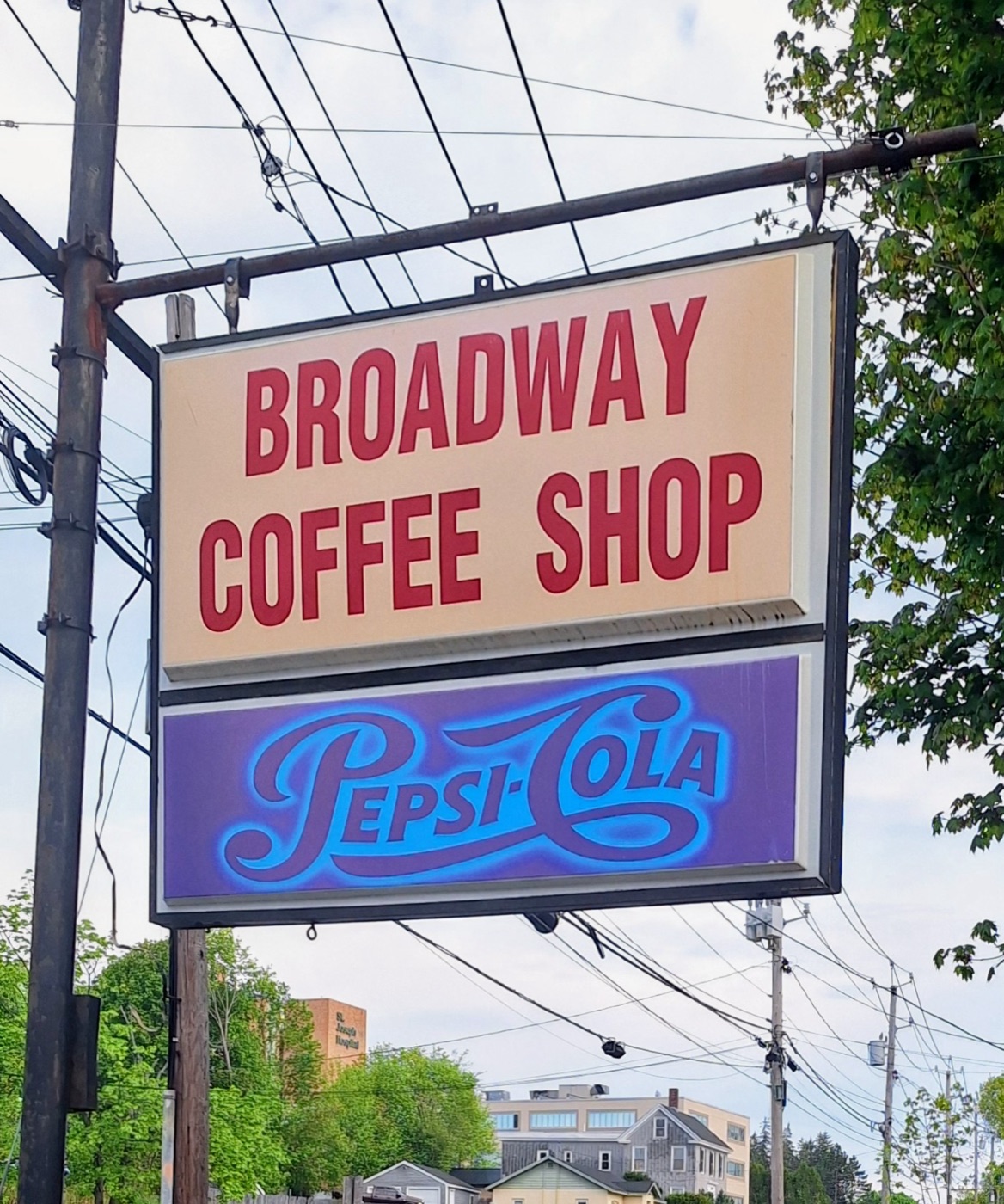 The roadside sign reading Broadway Coffee Shop in red letters above a Pepsi-Cola panel.